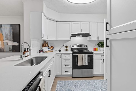 A modern kitchen with white cabinets and a black stove top oven.