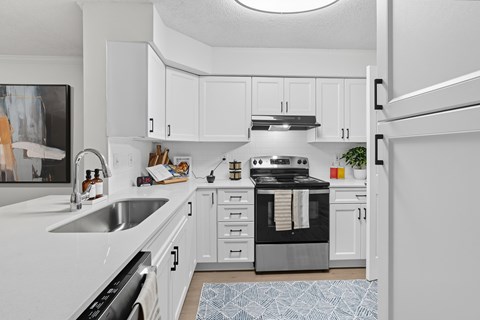 A modern kitchen with white cabinets and appliances.