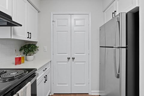 A black and white photo of a kitchen with a stove, refrigerator, and two doors.
