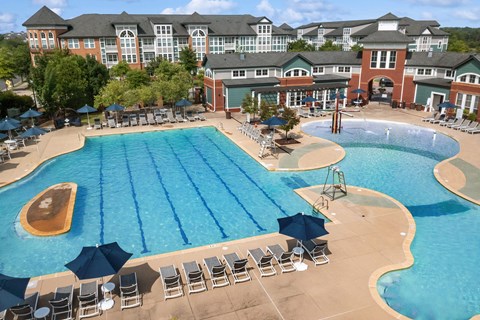 A large swimming pool with a diving board and sun loungers.