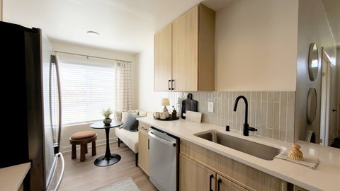 A kitchen with a black refrigerator, a white dishwasher, and a black sink.