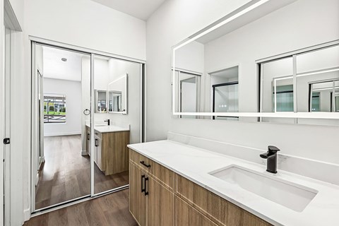 A bathroom with a sink, mirrors and a shower.