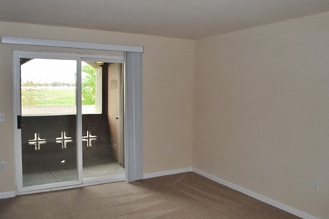 an empty living room with a sliding glass door to a patio