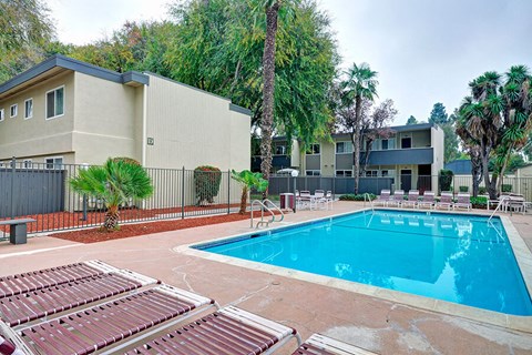 a swimming pool with chairs around it next to a building