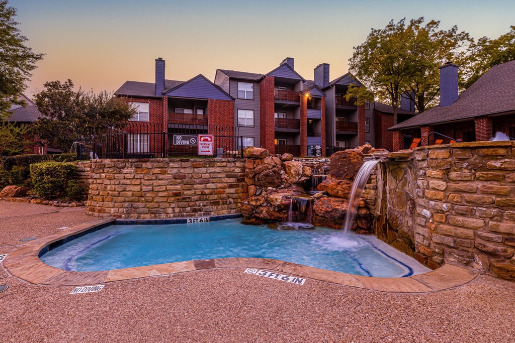a swimming pool with a waterfall in front of a hotel