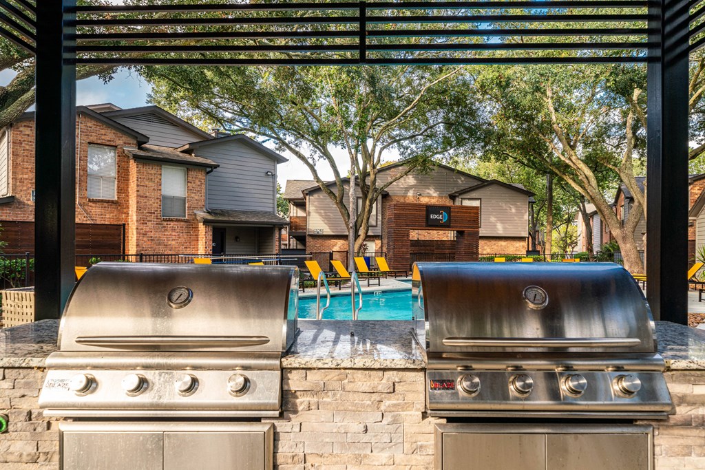 two bbqs and a pool with houses in the background