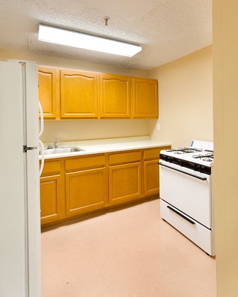 A kitchen with wooden cabinets and a white stove.