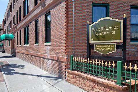 Bedell Terrace Apartments is a brick building with a green fence.