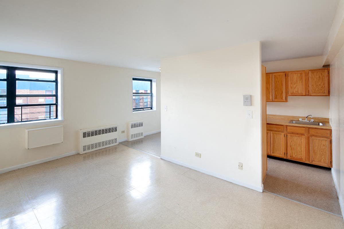 A spacious living room with a kitchenette and a window.