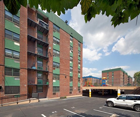 A red brick building with a green roof and a parking lot in front.