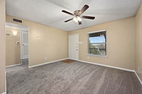 A room with a ceiling fan and carpeted floor.