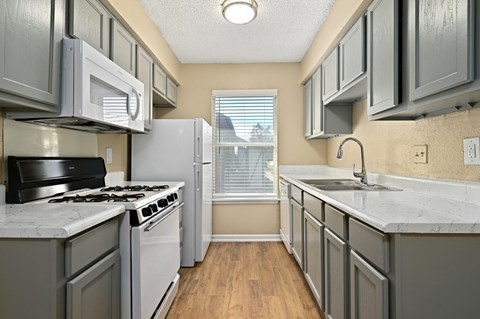 A kitchen with a stove top oven, microwave, and refrigerator.