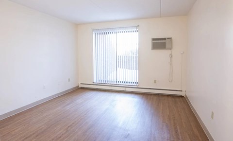 A room with wooden flooring and a window with blinds.