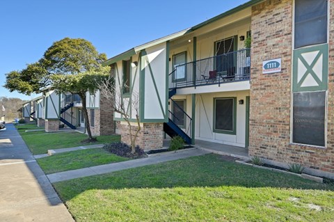 Apartment building with green bushes in front.