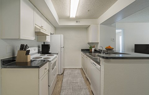 A kitchen with white cabinets and black countertops.