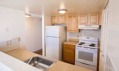 A kitchen with a white refrigerator, stove, and sink.