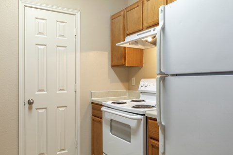 A white refrigerator stands in a kitchen next to a white door.