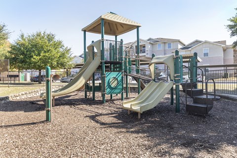 A playground with a green and tan slide and a brown and green play structure.