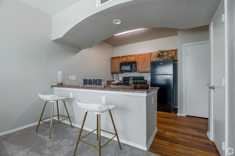 A kitchen with white countertops and gold bar stools.
