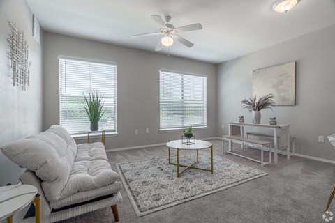 A living room with a white couch, a coffee table, and a ceiling fan.