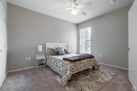 A bedroom with a bed, nightstand, and window.