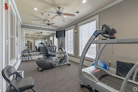 A home gym with a treadmill, exercise bike, and a television.