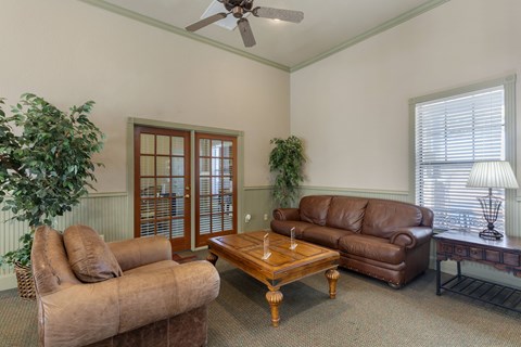 A living room with a brown couch, a wooden coffee table, and a ceiling fan.