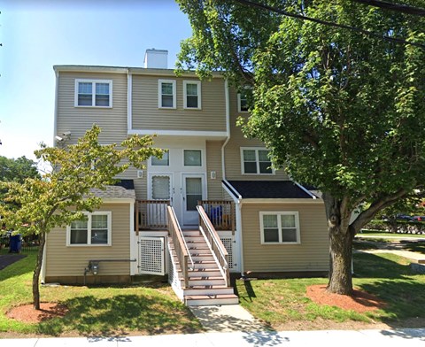 A two-story house with a beige exterior and a white door.