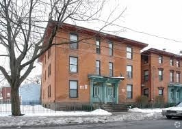 A red brick building with green doors and windows.