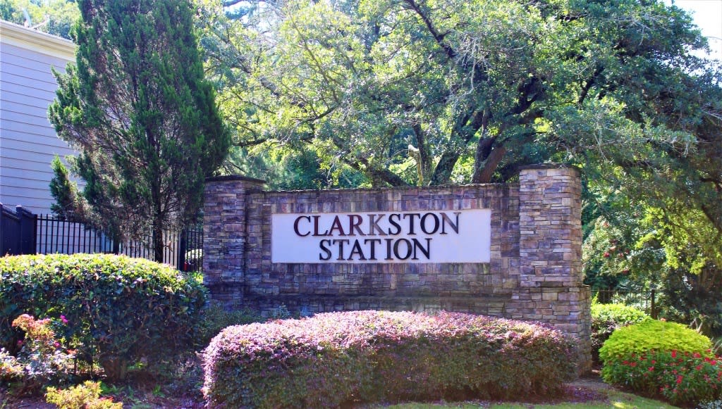 A sign that says Clarkston Station in front of a green hedge at Clarkston Station Apartments, Georgia