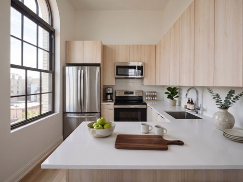 A kitchen with a white countertop and wooden cabinets.
