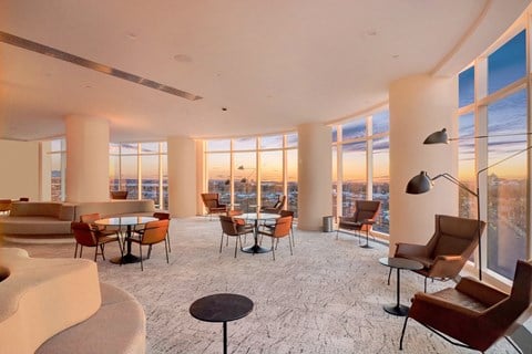 a living room with couches chairs and tables and a view of the city
