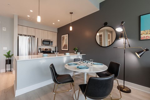 a dining room with a white table and chairs and a kitchen with a counter top