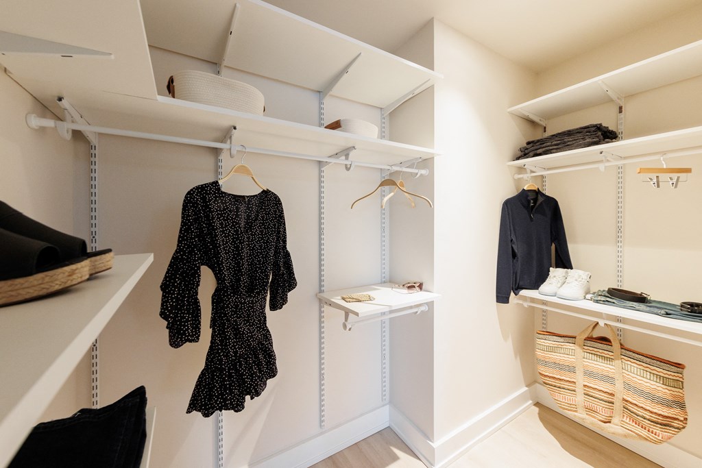 a walk in closet with shelves and a dress on a hanger