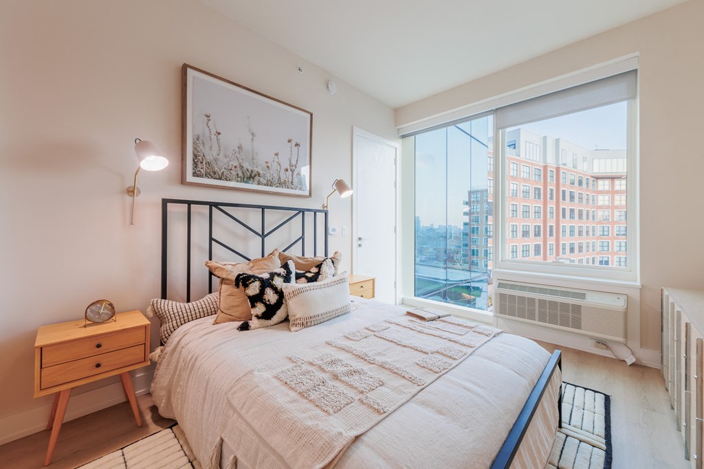 a bedroom with a large window and a bed with pillows