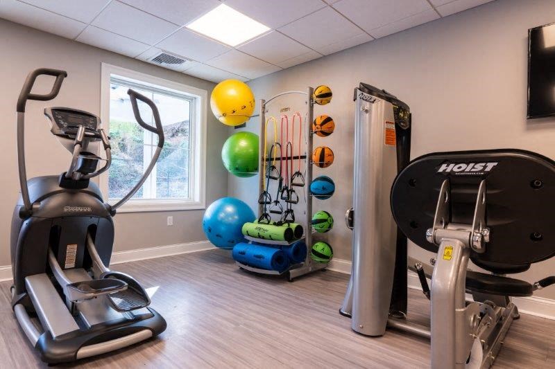 The corner of a fitness center with cardio equipment, weight equipment, tube bands, and exercise balls.