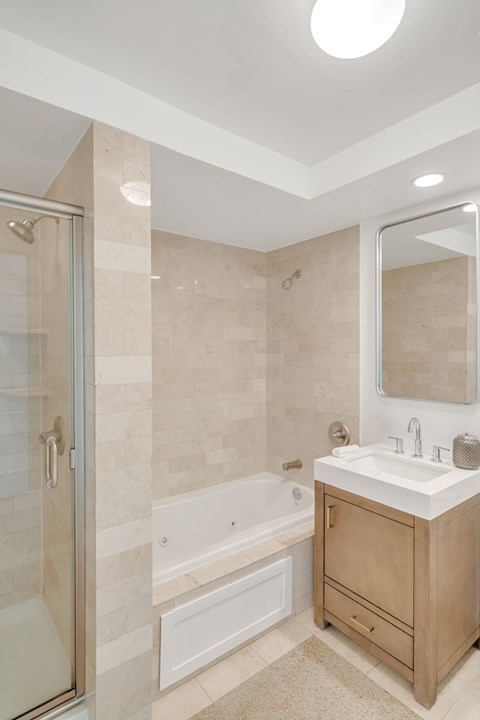 A bathroom with a sink, mirror, and bathtub.