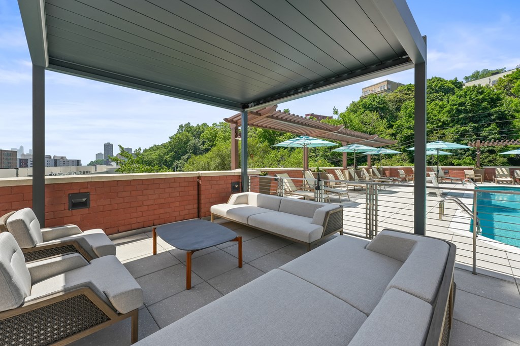 a rooftop patio with couches and chairs and a pool