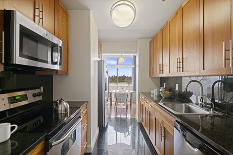 a kitchen with wooden cabinets and black counter tops and a sink and a window
