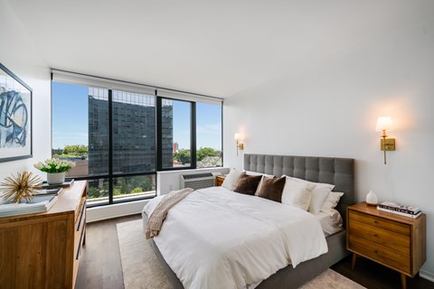 A bedroom with a large bed and a view of a city skyline.