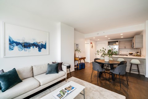 A living room with a white couch and a painting on the wall.