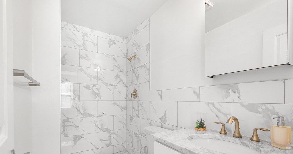 A bathroom with a marble tile shower and sink area.