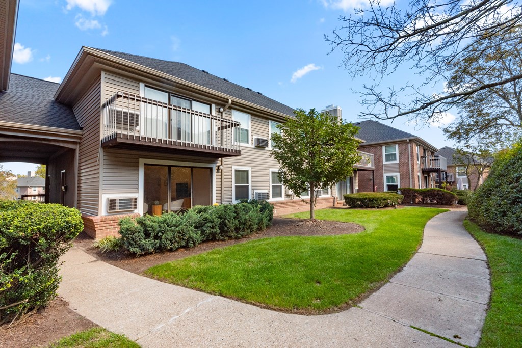 A residential building with a balcony and a small garden in front.