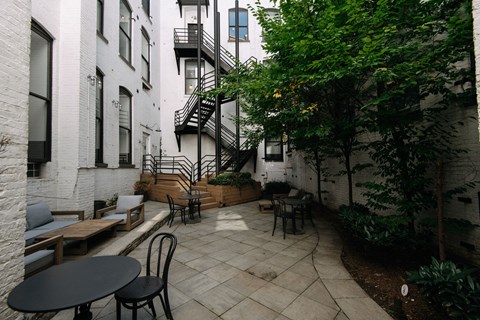 A patio with a table and chairs is surrounded by buildings.