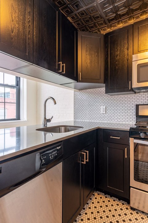 A kitchen with black cabinets and a white tiled backsplash.