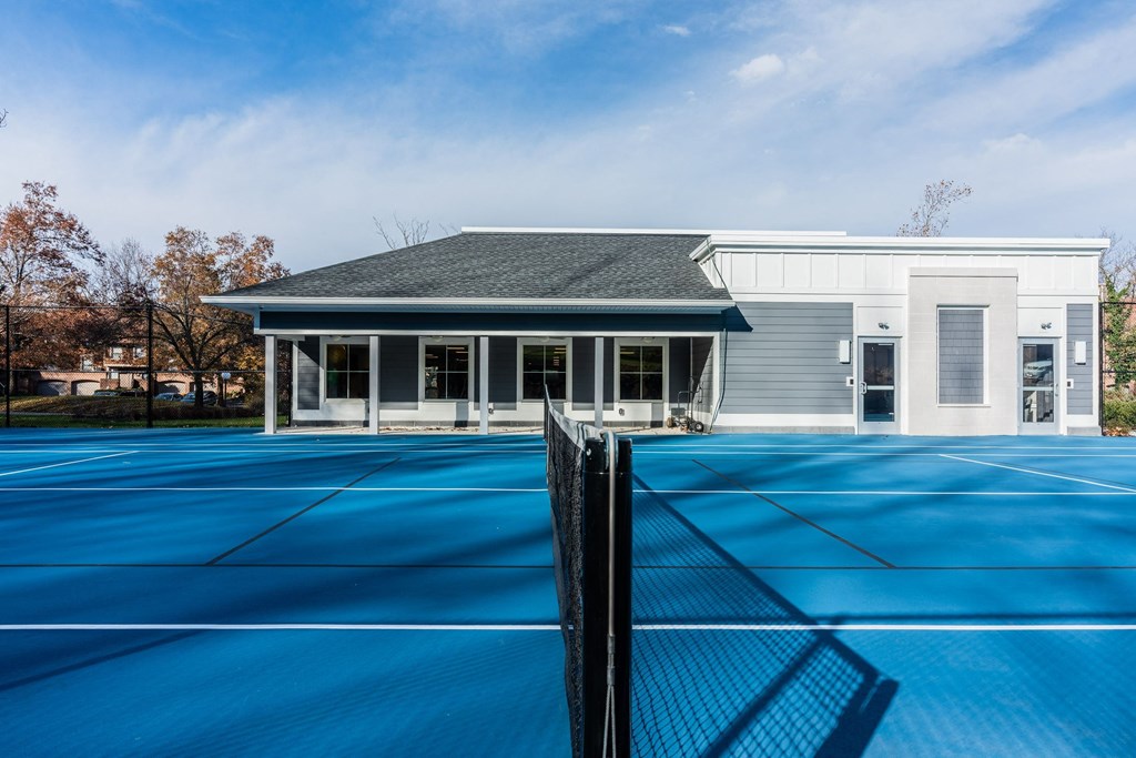A tennis court with clubhouse in the background.