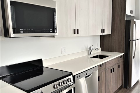 A modern kitchen with a black stove top oven and white cabinets.