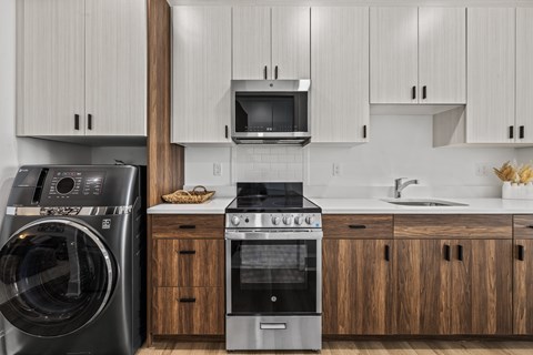 A modern kitchen with a washing machine, oven, and microwave.
