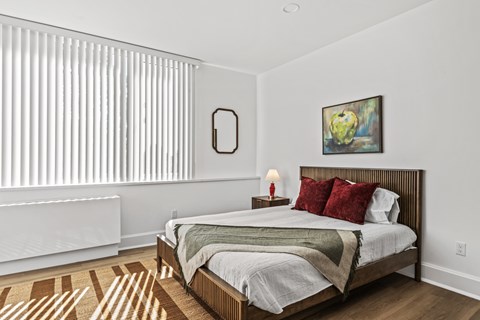 A bedroom with a bed, a lamp, and a painting on the wall.