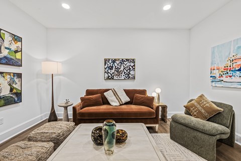 A living room with a brown couch and a painting on the wall.